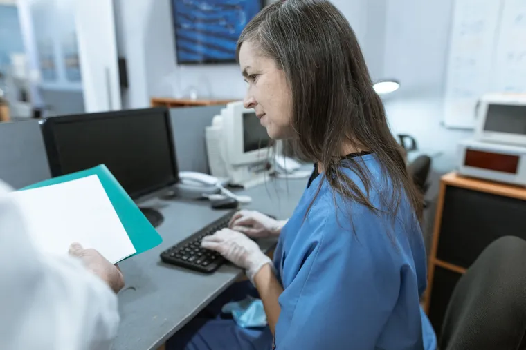 A healthcare worker entering information at a keyboard at an office workstation