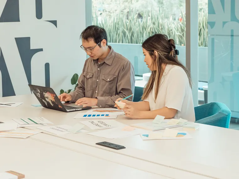 Two colleagues collaborating at a laptop in a bright modern office during the workday