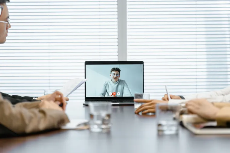 A US team meeting a remote colleague over a video call in a conference room